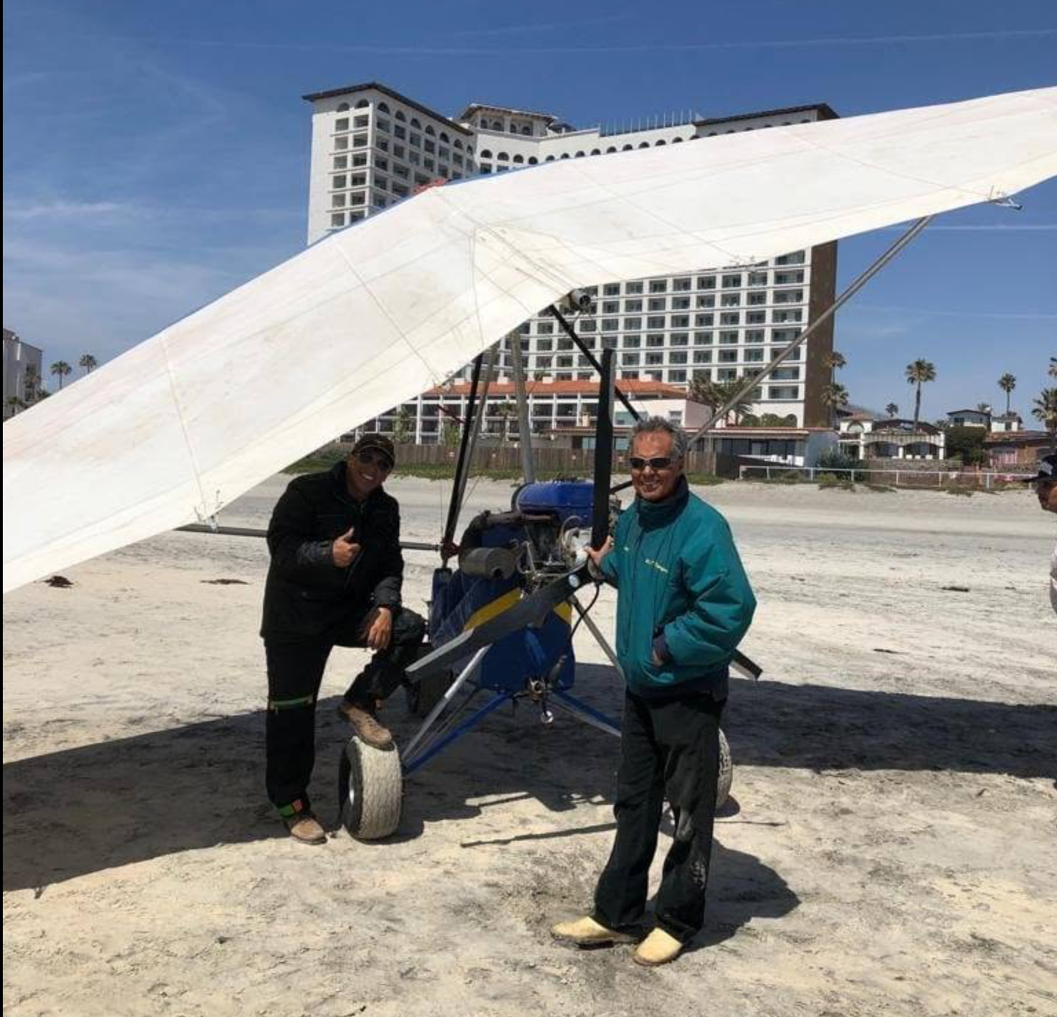 Pilotos junto al ultraligero en la playa